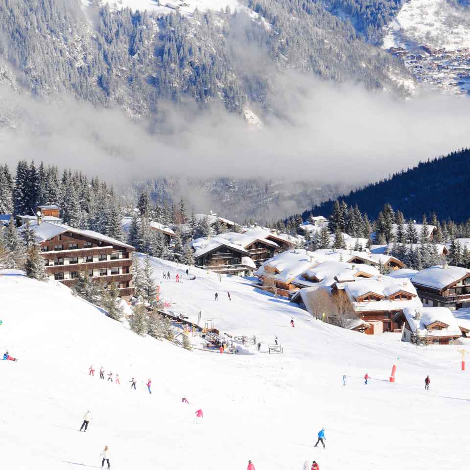 People skiing at a ski resorts which are covered in snow.